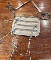 Front view showing three zip pockets, tassel pulls, chain strap