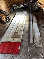 Stack of red and white aluminum siding sheets on garage floor