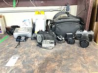 Group image of all cameras, printer dock, flash, meter, and bag