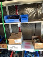 Shelving with hardware boxes, blue bins of screws and jars visible