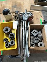 Group shot of ratchet heads, handles, die heads and loose dies in bins