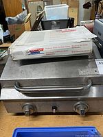 Top view of stainless steel BBQ with boxed Barbecue Genius cooking grids on lid