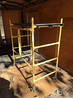 Full view of yellow rolling scaffold inside shed