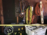 Overall lot on pegboard: cords, bungees, level, cord reel, basket