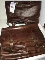 Two leather briefcases stacked, showing exterior styles and hardware