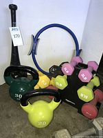 Group shot of kettlebells, mace club, Pilates ring, dumbbells on rack and loose neoprene dumbbells