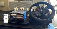 Logitech G29 steering wheel, pedal base and stack of six PS4 game cases