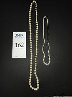 Both pearl necklaces laid flat for full view and length comparison