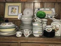 Front view of stacked dinnerware showing French Garden pattern and serving pieces