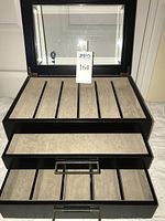 Watch case open showing slotted top compartment and drawers