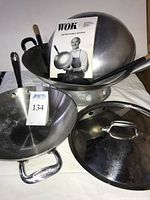 All items grouped: All-Clad pan with lid, carbon steel wok, utensils, booklet