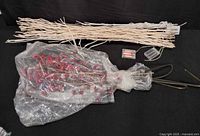 White twig lighted branches bundled; plastic-wrapped red berry spray bundle; battery pack visible
