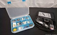 Cordless rotary tool in zippered case with charger, manual and accessory pack next to accessory organizer box