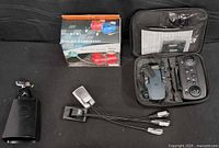 Overall lot showing air compressor box, drone case open with drone and remote, cowbell, reading lights