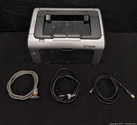 Top and front view of HP LaserJet printer with three cords laid out