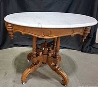 Full view of antique oval marble top table showing base and casters