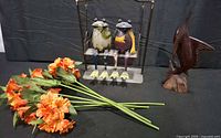 Overall lot view showing frog swing, orange artificial flower stems, wood swordfish carving