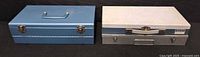 Two metal storage boxes closed, showing exterior colors, handles and latches