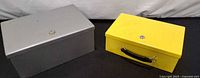 Grey and yellow cash boxes closed, showing finishes and locks