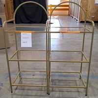 Front view of both gold-tone 3-tier glass shelving units