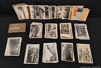 Overall lot showing multiple stacks of black-and-white postcards, souvenir booklet, and instruction cards