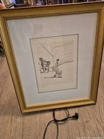 Full view of framed print on floor with power cord for scale