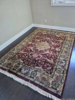 Entire rug on floor showing overall pattern and fringe