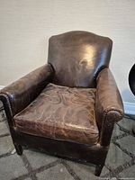 Front view of brown leather armchair showing overall style and wear