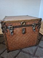 Front and side view of vintage studded leather steamer trunk showing latches and handle