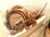 Overview of copper tubing coils and boxes of fittings in bathtub