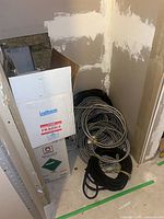 Overall view of box and multiple coils of conduit and cable in alcove