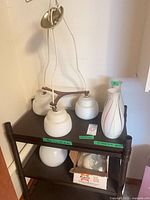 Pendant fixture with three socket arms, three globes and two striped vases on shelf