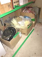 Overview of two boxes on floor containing cables, zip ties and hardware