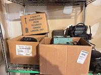 Shelf with two cardboard boxes containing compressors and parts; Tecumseh box visible