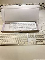 Both keyboards side by side, OMOTON in open box, Apple Magic Keyboard front