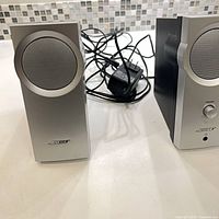 Front view of both Bose speakers with wiring and power adapter