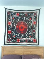 Full view of square embroidered Suzani hanging on wall above headboard