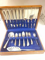 Open chest showing full flatware set arranged in blue felt slots