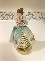 Front view of porcelain lady figurine showing fan, dress colors, base