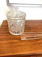 Ice bucket with lid and tongs on wood surface