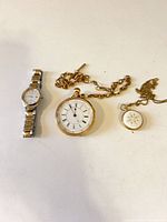 All three watches laid out: Citizen wristwatch, gold-tone pocket watch with chain, small pendant watch