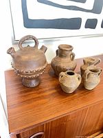Five pottery vessels grouped on wood surface