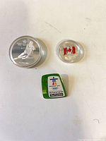 Group shot of both coins in capsules and Olympic pin