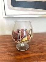 Clear glass brandy snifter containing assorted matchbooks