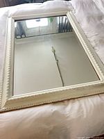 Full view of white framed mirror on bed