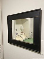 Full view of rectangular wooden frame mirror mounted on wall