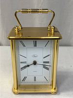 Front view of brass carriage clock showing dial and handle