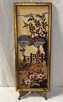 Full view of framed needlepoint on stand