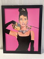 Full view of framed pop art print of Audrey Hepburn against pink background