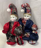 Both porcelain clown dolls seated side by side